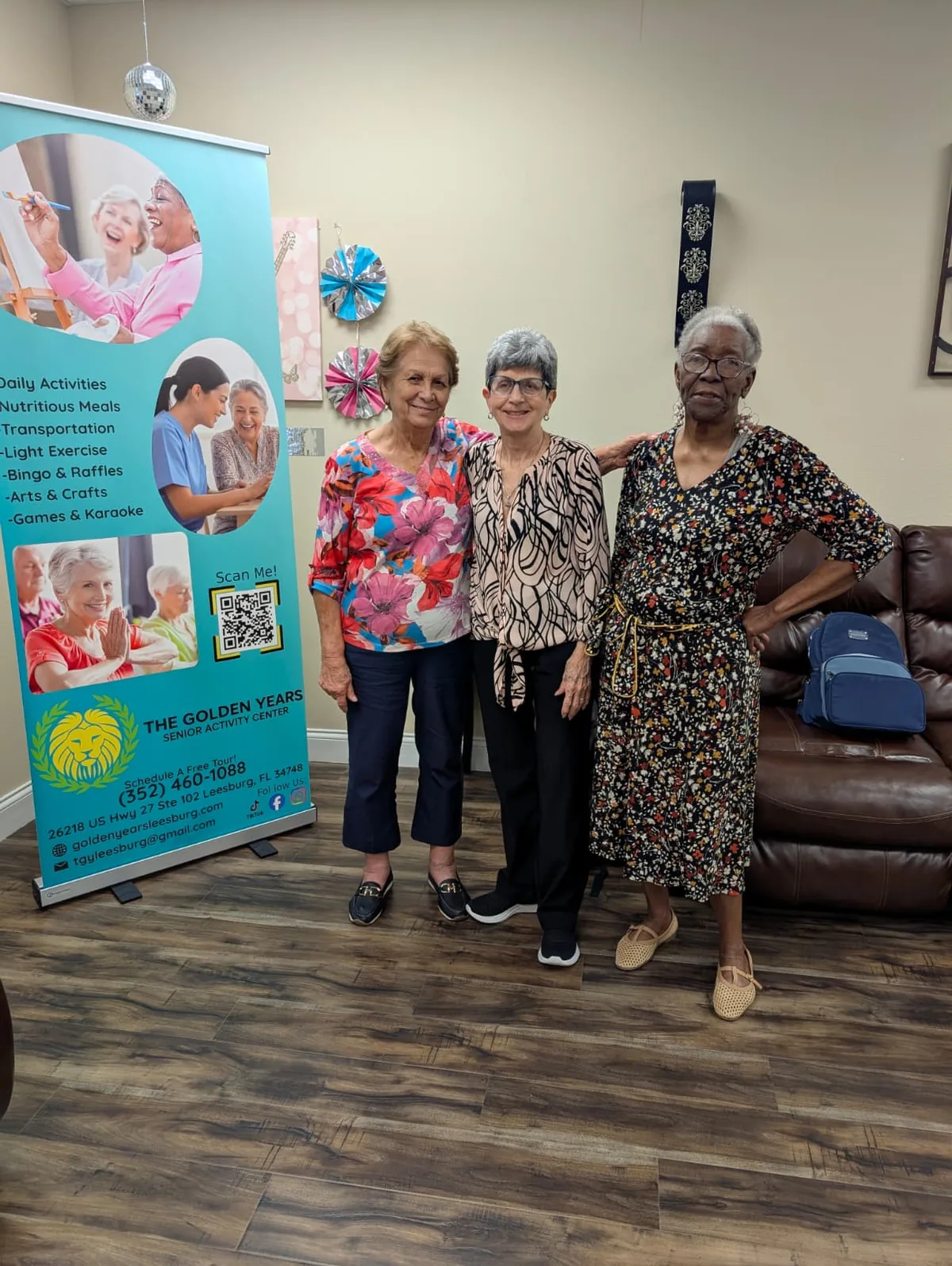 Three members standing together beside The Golden Years banner at the center